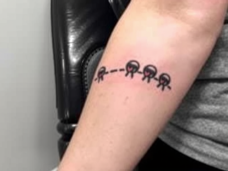 Close-up of a small roly poly isopod next to a tattoo of three roly polies on a person's left arm, showcasing whimsical and nature-inspired body art.