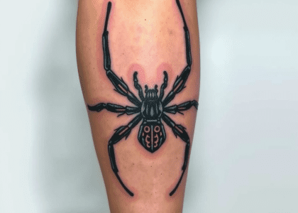 Tattoo of a spider intricately designed on a person's leg, showcasing detailed artwork and vibrant ink colors.